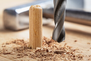 drill bit makes hole in wooden oak board for wooden dowel.