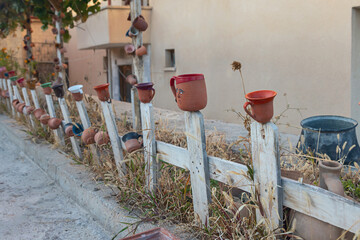 many small old earthenware jugs hang on a wooden fence as decoration