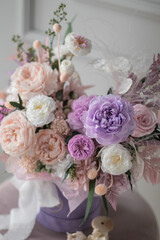 Beautiful composition with peonies and roses in a purpl box on pink chair. Bouquet of tenders peonies a girl for mother's day, valentine's day, Woman's day 8 march.