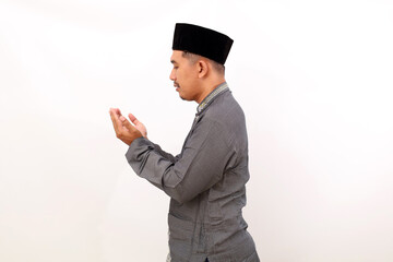 Side view of asian muslim man standing with praying hand gesture. Isolated on white background