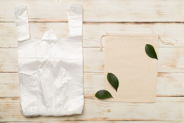 Plastic and fabric bag on wooden background, top view. Biodegradable products concept