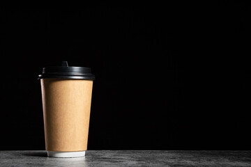 Brown Paper cup of coffee or tea on a black background with copy space, mock up.