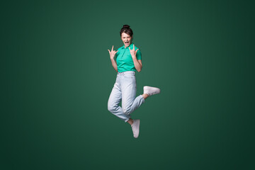 Full body photo of crazy funky woman jump up in air making horned signs screaming isolated on green...