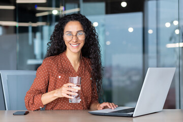 Portrait of Hispanic woman inside modern office at work, businesswoman smiling and looking at...
