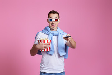 man using remote controller watching movie with big bucket of popcorns