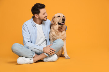 Happy man with his cute Labrador Retriever on yellow background. Space for text