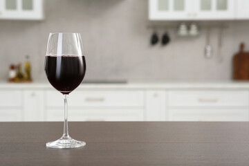 Glass of red wine on countertop in kitchen, space for text