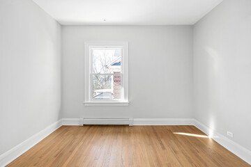 Modern and Neutral Bedroom. Vacant room with hardwood floors and window for virtual staging.