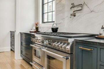 Transitional Kitchen with Stainless Steel Luxury Appliances. Transitional kitchen design with marble backsplash. Styled counter and stove with pot filler. - obrazy, fototapety, plakaty