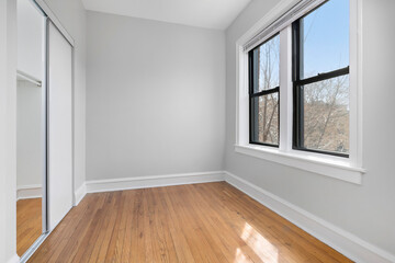 Modern and Neutral Bedroom. Vacant room with hardwood floors and window for virtual staging.
