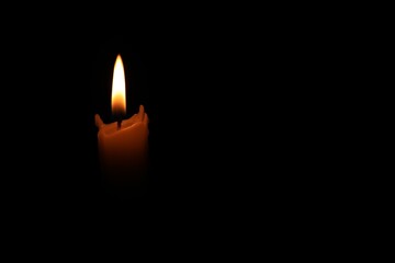 Burning wax candle in darkness. Space for text