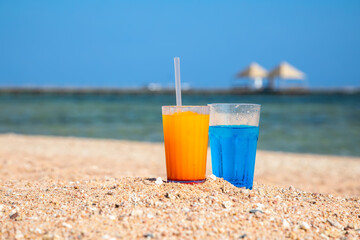 Beautiful cocktails on the sand near the sea shore. Glasses with summer cocktails. Yellow sand on the beach. Sunny summer day.