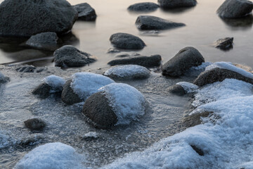 Steine am Seeufer mit Eis und Schnee 
