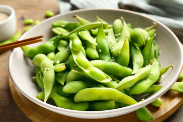 Green edamame beans in pods served on wooden table, closeup