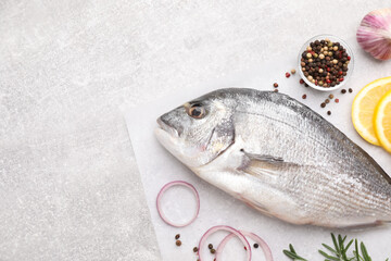 Flat lay composition with fresh raw dorado fish and ingredients on light grey table, space for text