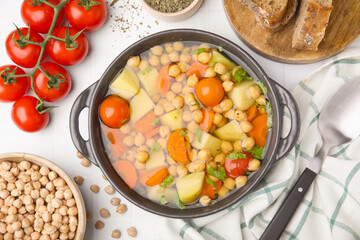 Flat lay composition of tasty chickpea soup served on white tiled table