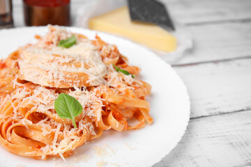 Delicious pasta with tomato sauce, chicken and parmesan cheese on white wooden table, closeup. Space for text