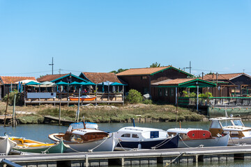 Fototapeta na wymiar Bassin d’Arcachon (Gironde, France). Pinasses traditionnelles et cabanes ostréicoles au port ostréicole de La Teste de Buch