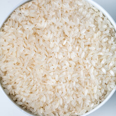 White bowl of white rice on white background, top view, copy space. Close-up.