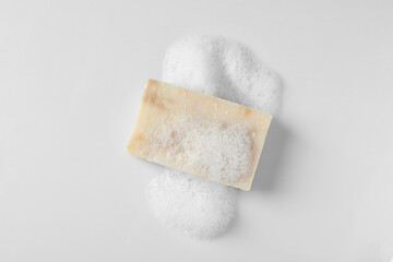 Soap with fluffy foam on white background, top view