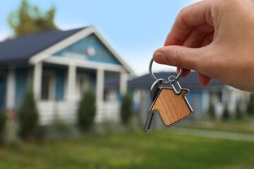 Woman holding house keys outdoors, closeup with space for text. Real estate agent