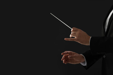 Professional conductor with baton on black background, closeup. Space for text - obrazy, fototapety, plakaty