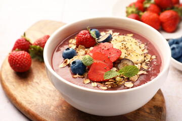 Delicious smoothie bowl with fresh berries, banana and granola on table, closeup