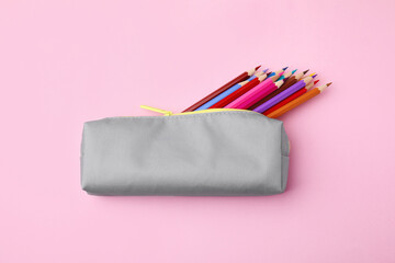 Many colorful pencils in pencil case on pink background, top view