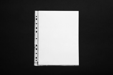 Punched pocket with paper sheet on black background, top view