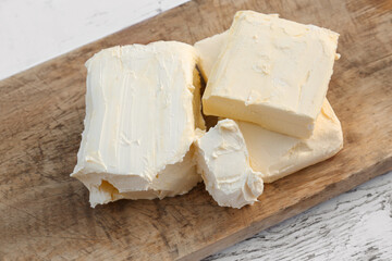 Board with tasty homemade butter on white wooden table, closeup
