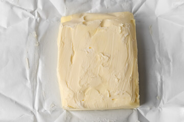 Piece of tasty homemade butter on paper wrap, top view