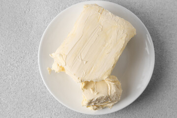 Plate with tasty homemade butter on white textured table, top view