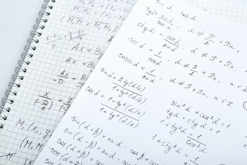 Sheets of paper with different mathematical formulas on table, closeup