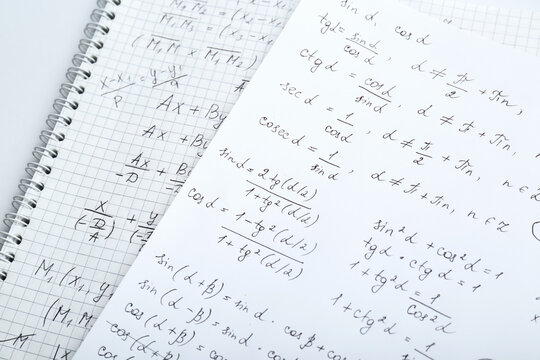 Sheets of paper with different mathematical formulas on table, closeup