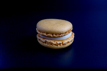 Colorful vanilla colored macaron on a dark background.