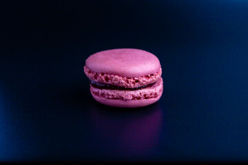 Colorful pink macaron on a dark background.