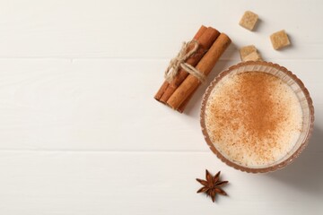 Fototapeta na wymiar Delicious eggnog with anise and cinnamon on white wooden table, top view. Space for text