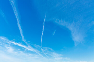 A bright blue sky with traces of condensation from airplanes. Space for text.