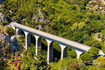 White Arc Bridge, Viaduct of Eze or Devil bridge, over Alpes canyon seen from historic town of Eze rising over Azure Cost of Mediterranean Sea in France