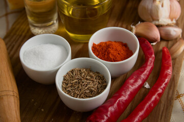 Close-up of different spices, such as paprika powder, garlic heads, salt, red pepper, oil