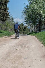 A man riding a bicycle on the driveway in the park.