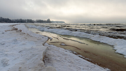 winter landscape from the seashore, lying pieces of ice on the seashore, sand and ice texture in the dunes