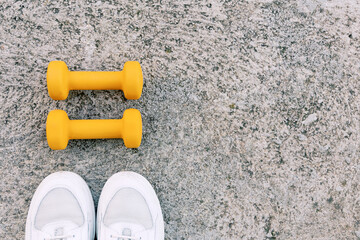 Top-down view of yellow dumbbells and white sneakers, ideal for fitness-themed content.