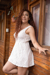 Naklejka premium attractive young latin woman with curly red hair, model with natural beauty wears light dress, fashion and relaxed lifestyle