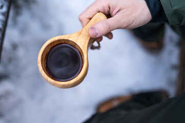 Man holding a Finnish wooden cup, kuksa, with coffee in it. Finland