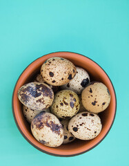 Obraz premium Raw fresh quail eggs in brown bowl. Top view. Green background.