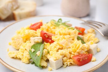 Plate with delicious scrambled eggs, tofu and tomatoes on table, closeup