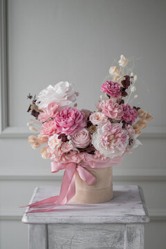 A luxurious bouquet of flowers in a hat box. Composition with pink and white flowers and eucalyptus in a round box. Modern Floristry.