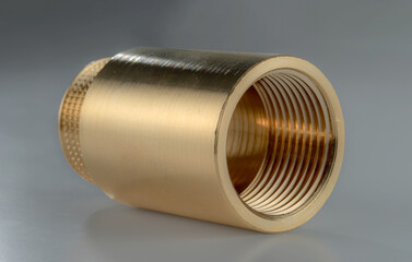 Brass regular coupling with internal and external thread isolated on a grey background.