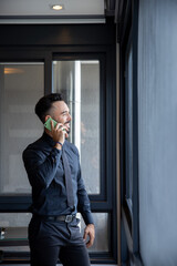 Handsome businessman in black suit talking on the phone in the office